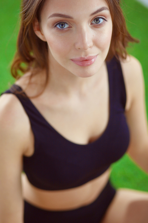 Woman sitting with crossed legs on the green grass.の写真素材