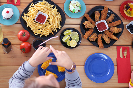 People with drinks while sitting at the dining table. Food on the table. Food on the table. People eat fast foodの写真素材