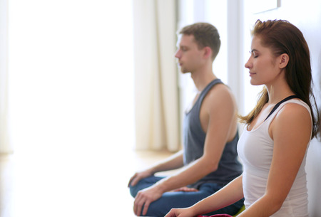 Young healthy couple in yoga position on white backgroundの写真素材