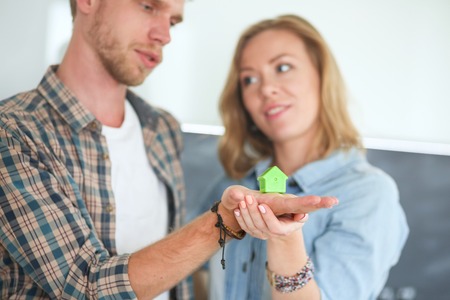 Model house in hand of a couple, standing in new home. Model house.の写真素材