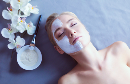 Face mask.Beautiful young girl at spa ,cosmetician woman applying facial maskの写真素材