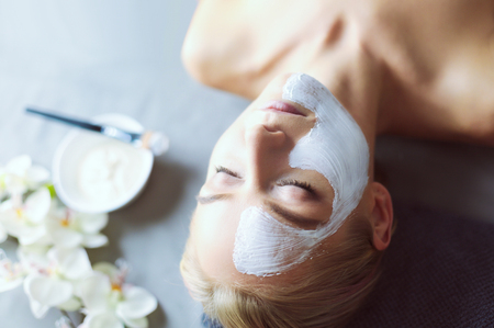 Face mask.Beautiful young girl at spa ,cosmetician woman applying facial maskの写真素材