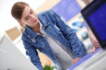 Two young woman standing near desk with instruments, plan and laptop.の写真素材