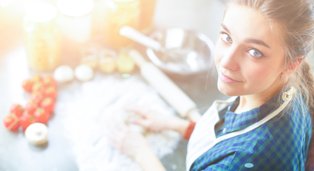 Beautiful woman cooking cake in kitchen standing near deskの写真素材