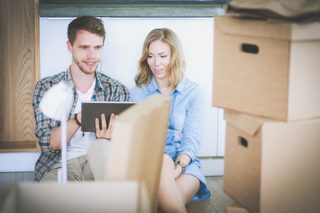 Young couple moving in new home.Sitting and relaxing after unpacking.Looking something on laptop. Young coupleの写真素材