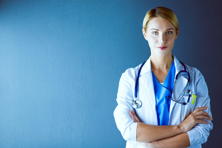 Portrait of young woman doctor with white coat standing in hospital.の写真素材