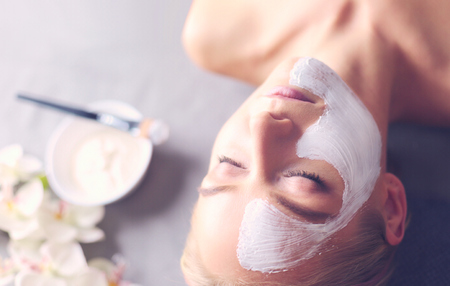 Face mask.Beautiful young girl at spa ,cosmetician woman applying facial maskの写真素材