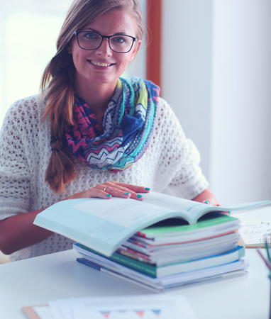 Young woman sitting at a desk among books. Studentの写真素材