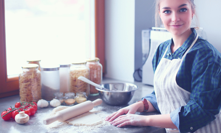 Beautiful woman cooking cake in kitchen standing near desk.の写真素材