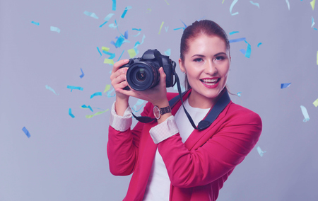 Beautiful happy woman with camera at celebration party with confetti . Birthday or New Year eve celebrating conceptの写真素材