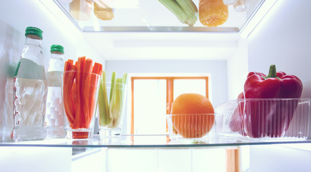 Portrait of female standing near open fridge full of healthy food, vegetables and fruits. Portrait of femaleの写真素材
