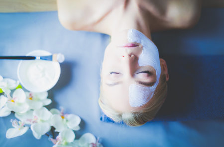 Face mask.Beautiful young girl at spa ,cosmetician woman applying facial mask