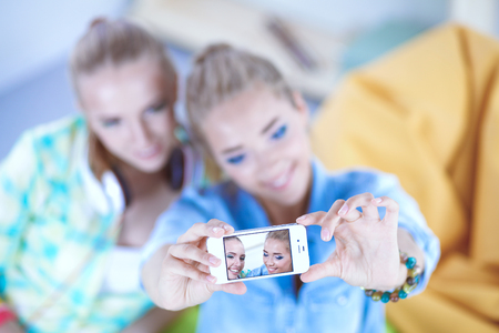 Portrait of a happy two smiling girls making selfie photo on smartphoneの写真素材