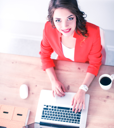 Attractive woman sitting at desk in office, working with laptop computerの写真素材