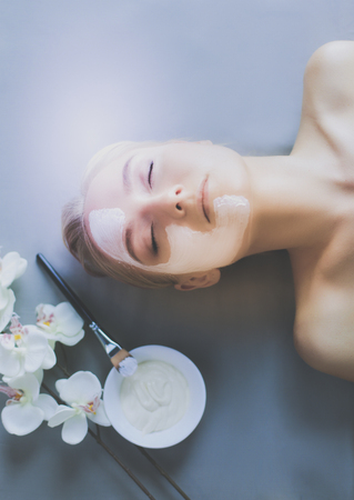 Face mask.Beautiful young girl at spa ,cosmetician woman applying facial maskの写真素材