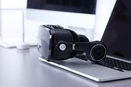 Virtual reality goggles on desk with laptopの写真素材