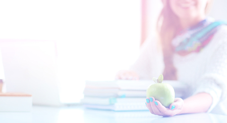 Young woman sitting at a desk among booksの写真素材