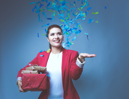 Beautiful happy woman with gift box at celebration party with confetti . Birthday or New Year eve celebrating conceptの写真素材