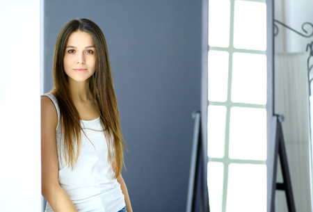 Young woman looking herself reflection in mirror at homeの写真素材