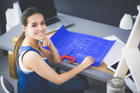Young woman sitting on the desk in officeの写真素材