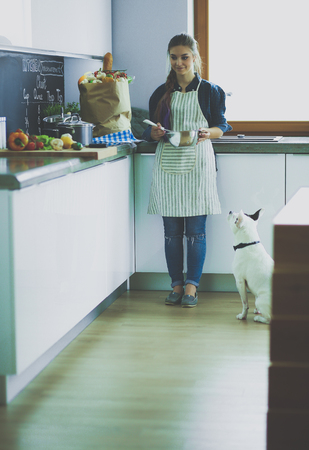 Portrait of young woman standing against kitchen background.の写真素材