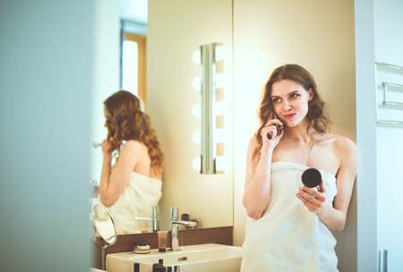 Young woman standing on bathroom with phone.の写真素材