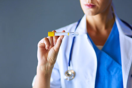 Female medical or research scientist or doctor using looking at a test tube of clear solution in a...