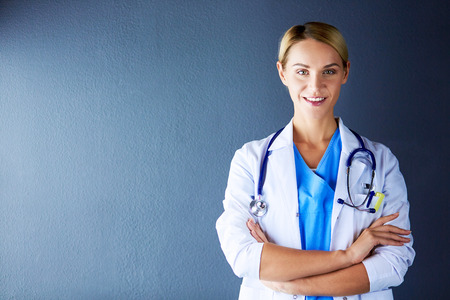 Portrait of young woman doctor with white coat standing in hospital.の写真素材