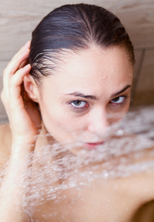 Young beautyful woman under shower in bathroom.の写真素材