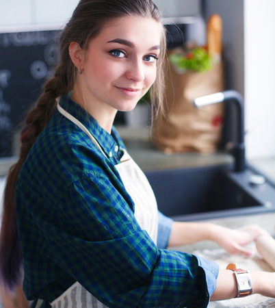 Beautiful woman cooking cake in kitchen standing near desk.の写真素材