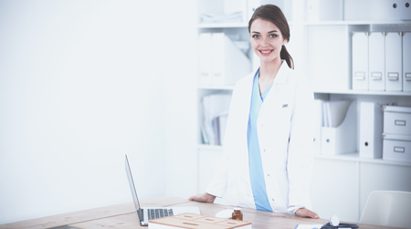 Portrait of young woman doctor with white coat standing in hospitalの写真素材