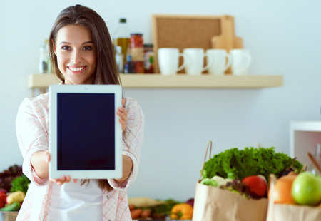 Young woman in the kitchen, using her tabletの写真素材