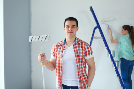 Portrait happy smiling young couple painting interior wall of new house. Young coupleの写真素材