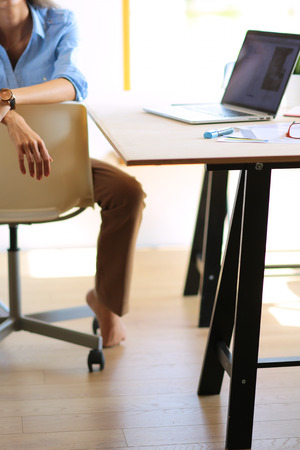 Young woman sitting at office table with laptop. Young woman. Laptopの写真素材
