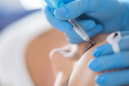 Permanent makeup for eyebrows. Closeup of beautiful woman with thick brows in beauty salon.の写真素材