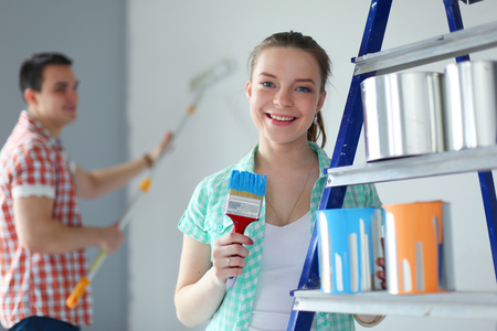 Portrait happy smiling young couple painting interior wall of new house. Young coupleの写真素材