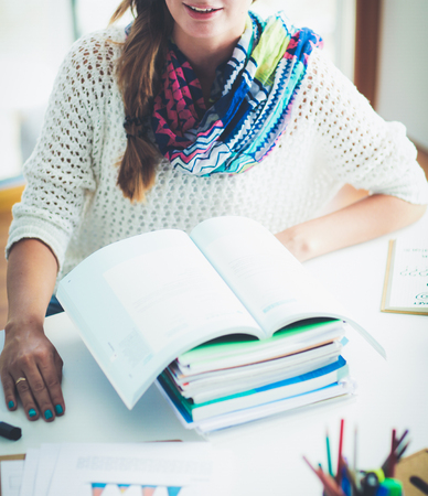 Young woman sitting at a desk among books. Studentの写真素材