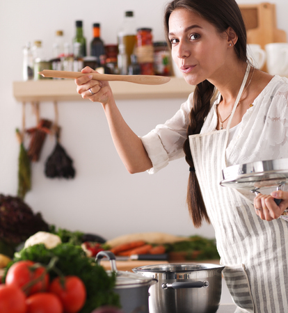 Cooking woman in kitchen with wooden spoonの写真素材