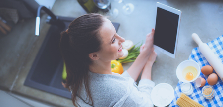 Beautiful woman cooking cake in kitchen standing near desk.の写真素材