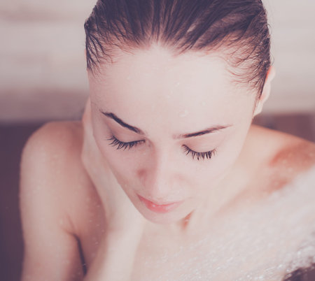 Young beautyful woman under shower in bathroom.