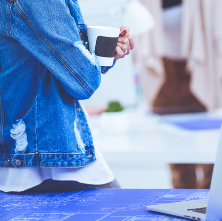 Two young woman standing near desk with instruments, plan and laptop.の写真素材