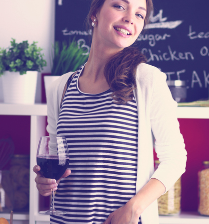 Pretty woman drinking some wine at home in kitchenの写真素材