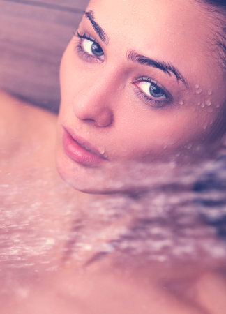 Young beautiful woman under shower in bathroom