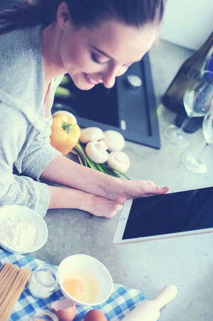 Beautiful woman cooking cake in kitchen standing near desk.の写真素材