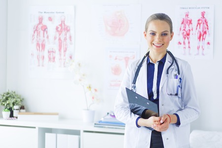 Smiling female doctor with a folder in uniform standingの写真素材