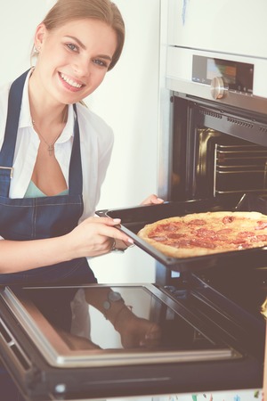 Happy young woman cooking pizza at homeの写真素材