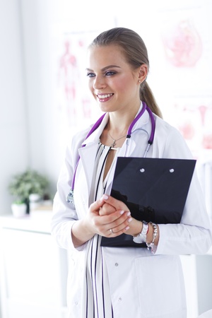 Smiling female doctor with a folder in uniform standingの写真素材