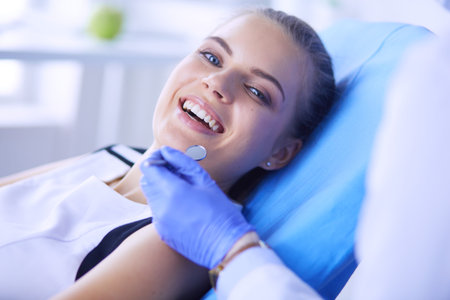 Young Female patient with pretty smile examining dental inspection at dentist office.