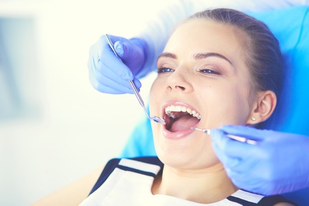 Young Female patient with open mouth examining dental inspection at dentist office.の写真素材