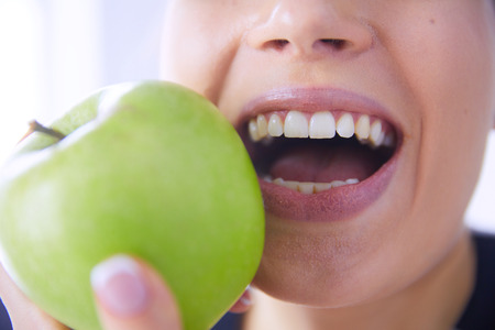 Close up portrait of healthy smiling woman with green appleの写真素材